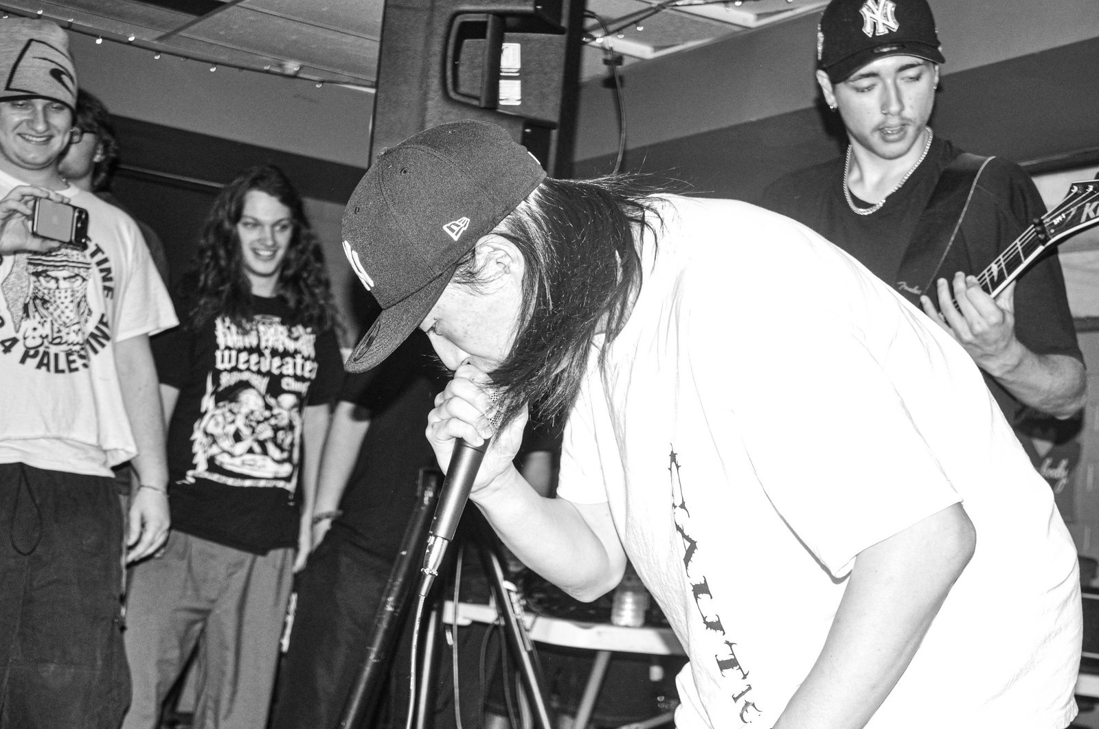 KNEED vocalist leaning into the mic while the crowd watches